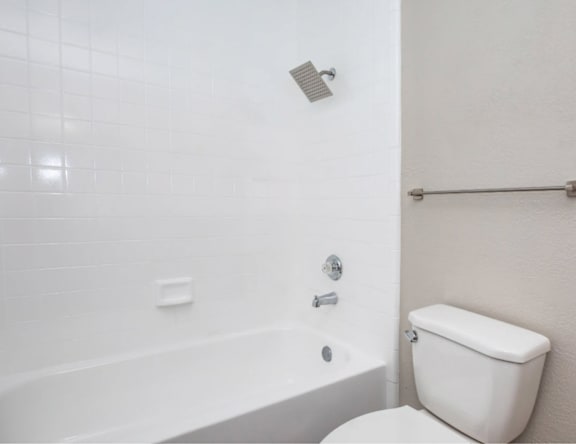 A white toilet sits next to a white bathtub in a bathroom.
