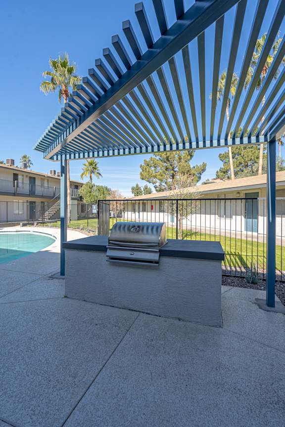 A poolside table under a blue striped awning.