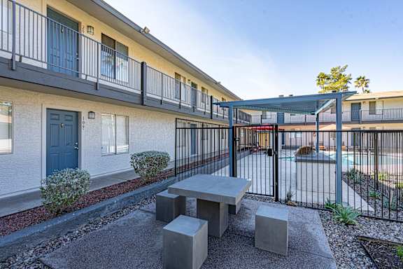 A patio with a table and chairs is surrounded by a black fence.