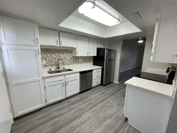 A kitchen with white cabinets and a black fridge.