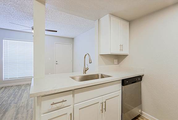 A kitchen with white cabinets and a stainless steel dishwasher.