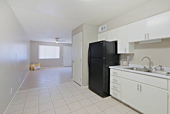 A kitchen with white cabinets and a black refrigerator.