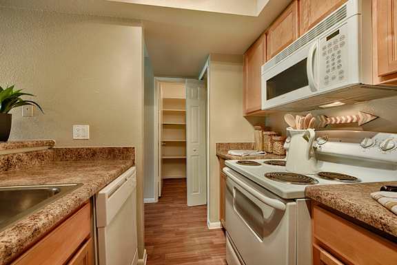 A kitchen with a stove, sink, and refrigerator.