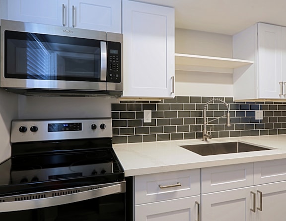 A kitchen with a black oven and white cabinets.