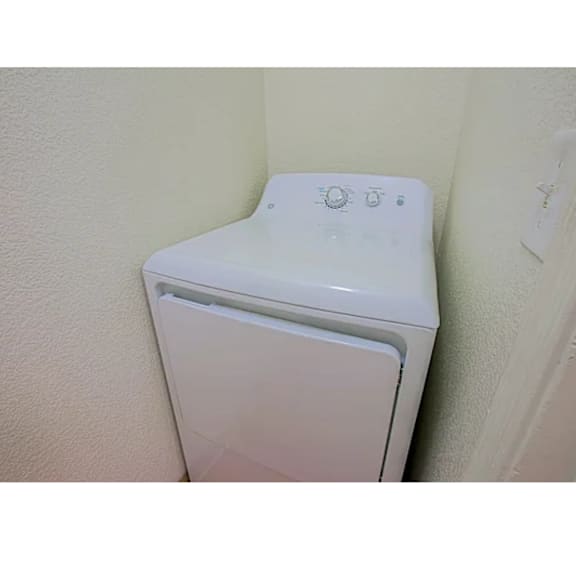 A white dryer is sitting in a corner.