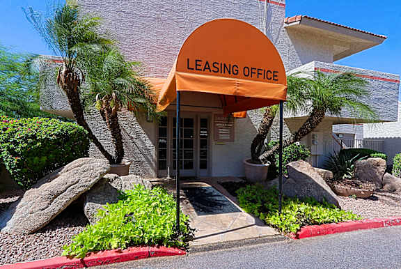 A leasing office is surrounded by rocks and palm trees.