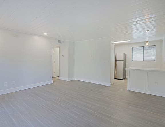 A spacious room with white walls and a wooden floor.
