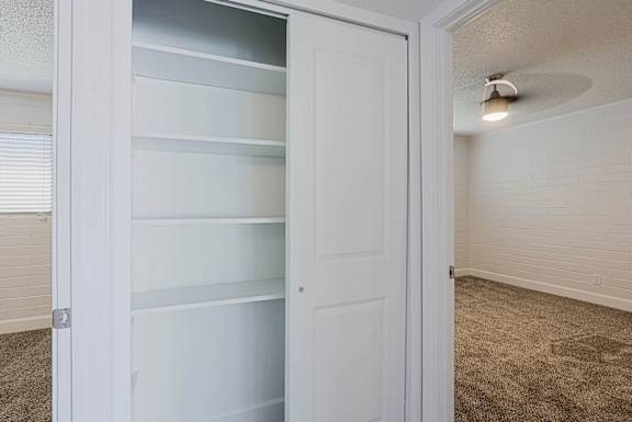 A white closet with a door open and shelves inside at Palm Villas Apartments, Arizona, 85257