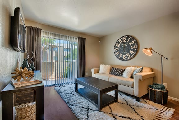 A living room with a couch, coffee table, and a clock on the wall.