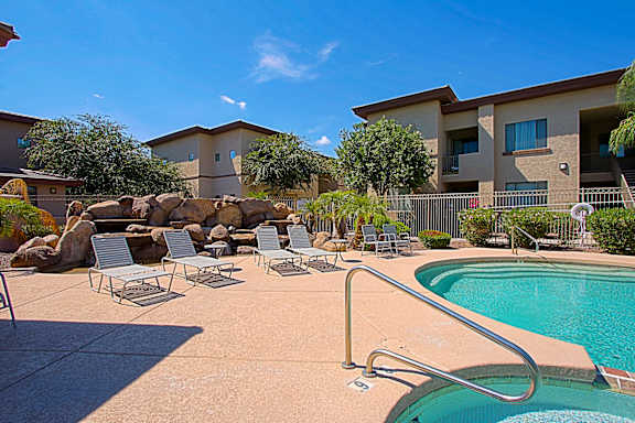 A swimming pool with a metal ladder and a few chairs.