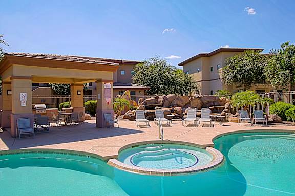 A pool with a slide and a hot tub in front of a house.
