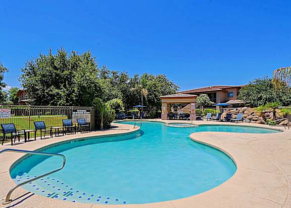 A large outdoor swimming pool with a slide and lounge chairs.