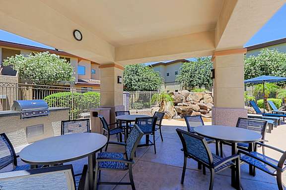 A patio with tables and chairs and a grill.