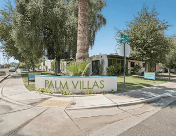 A sign that says Palm Villas in front of a building.