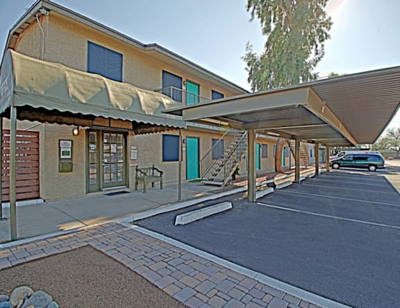 A building with a covered walkway and a car parked in the background.