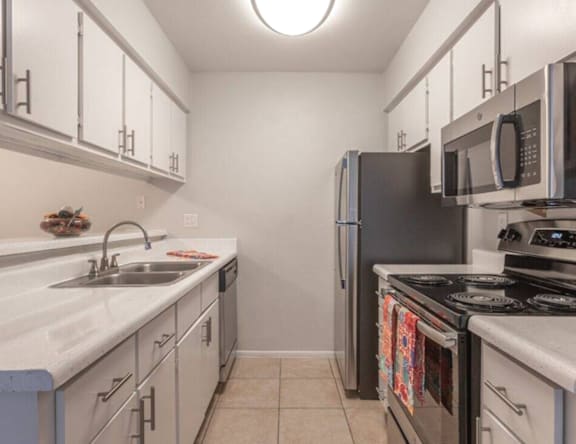 A kitchen with a black refrigerator and white cabinets.