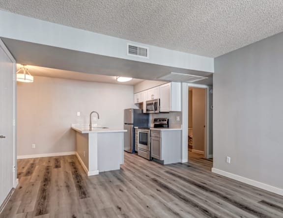 A kitchen with a white countertop and wooden flooring.