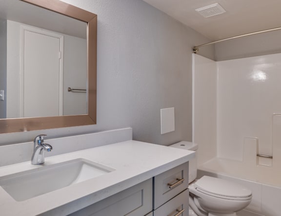 A white bathroom with a sink, toilet, and mirror.