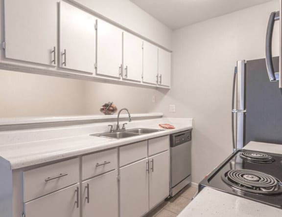 A kitchen with white cabinets and a stove top oven.
