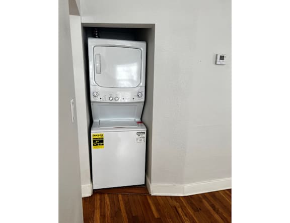A small white washing machine in a narrow space.