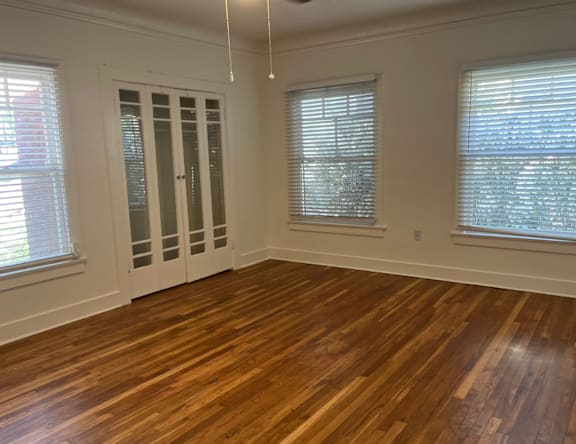 A room with wooden floors and two windows.