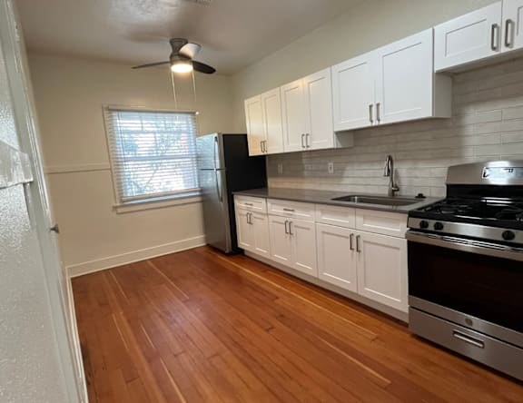 A kitchen with wooden floors and white cabinets.