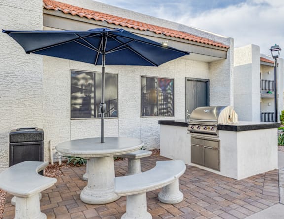 A patio with a table, chairs and an umbrella.