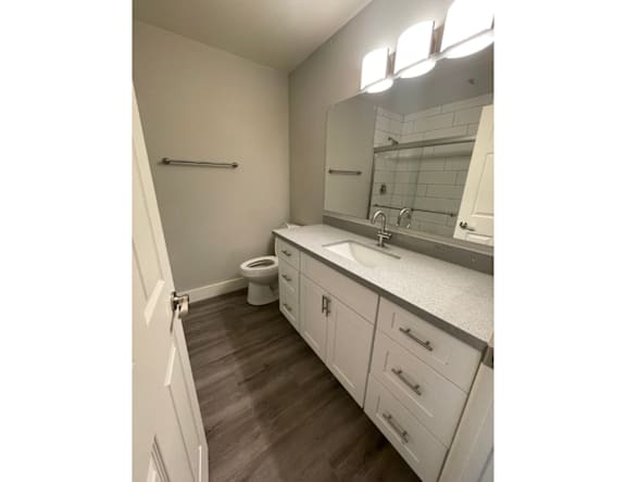 A bathroom with a toilet, sink, and mirror.