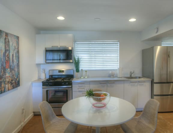 A modern kitchen with a white table and chairs.