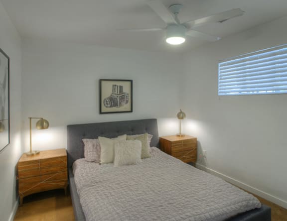 A bedroom with a bed, nightstands, and a ceiling fan.