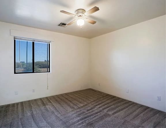 A room with a ceiling fan and carpeted floor.