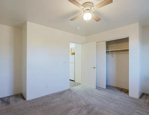 A room with a ceiling fan and carpeted floor.