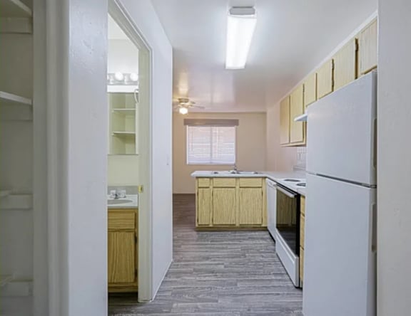 A kitchen with a white refrigerator and wooden cabinets.