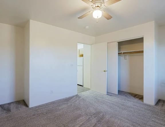A room with a ceiling fan and carpeted floor.