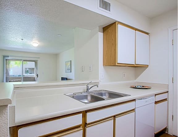 A kitchen with white countertops and wooden cabinets.
