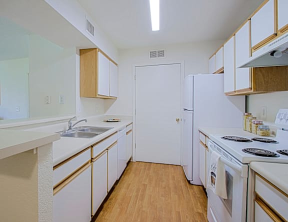 A kitchen with white appliances and wooden cabinets.