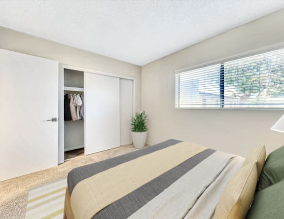 A bedroom with a bed, a plant, and a wardrobe.