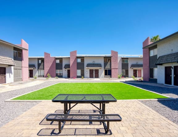 A picnic table is in the middle of a courtyard with a building in the background.