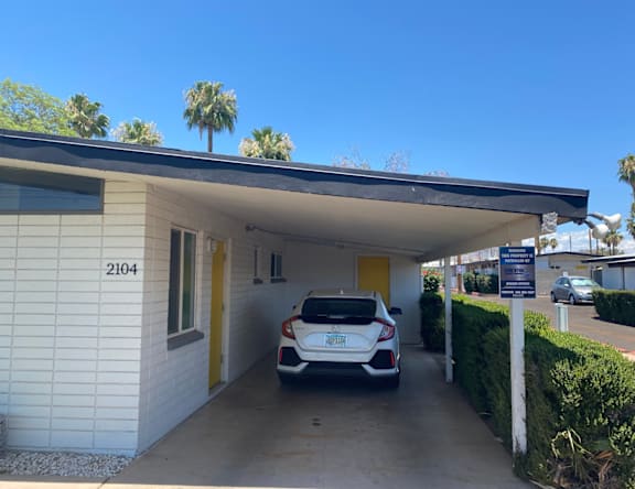 A white car is parked in a garage with a yellow door.