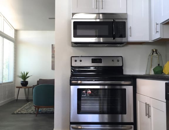 A modern kitchen with a black oven and white cabinets.