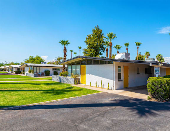 A building with a yellow door is surrounded by palm trees.