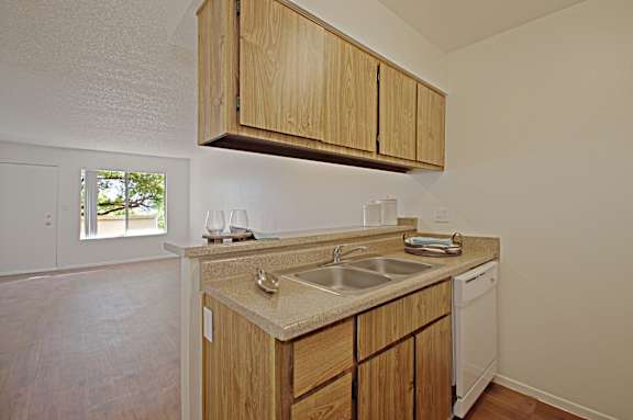 A kitchen with wooden cabinets and a white dishwasher.