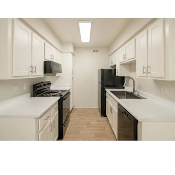 A kitchen with black appliances and white cabinets.