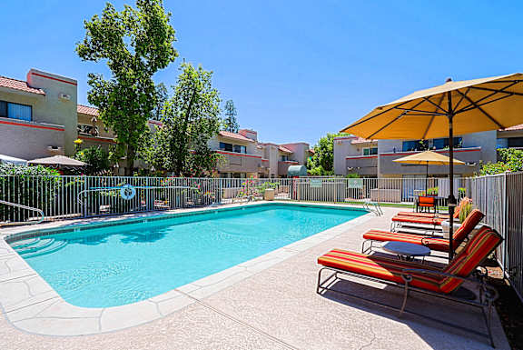 A pool surrounded by chairs and umbrellas.