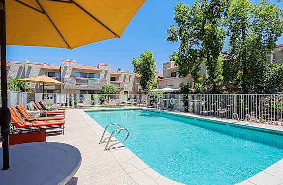 A pool surrounded by chairs and umbrellas.