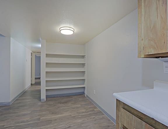 A room with a white counter and wooden shelves.