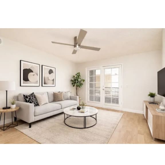 A living room with a grey sofa, a coffee table, and a ceiling fan.