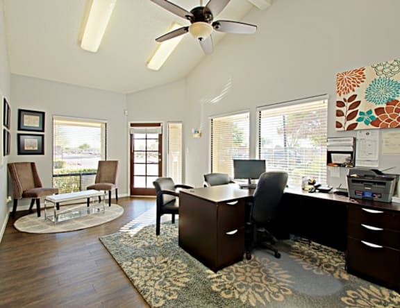 A room with a ceiling fan and a desk with a computer.