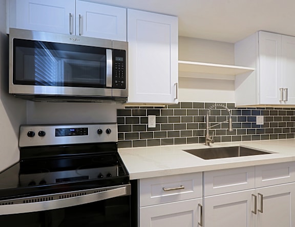 A kitchen with a black stove and white cabinets.
