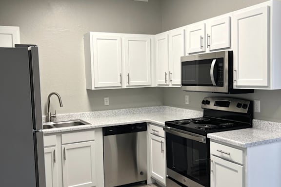 A kitchen with white cabinets and appliances.